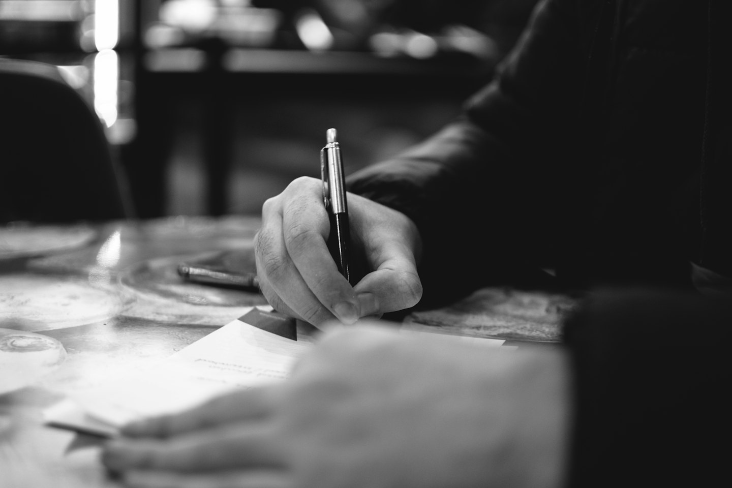 Hands writing with a pen on a document.