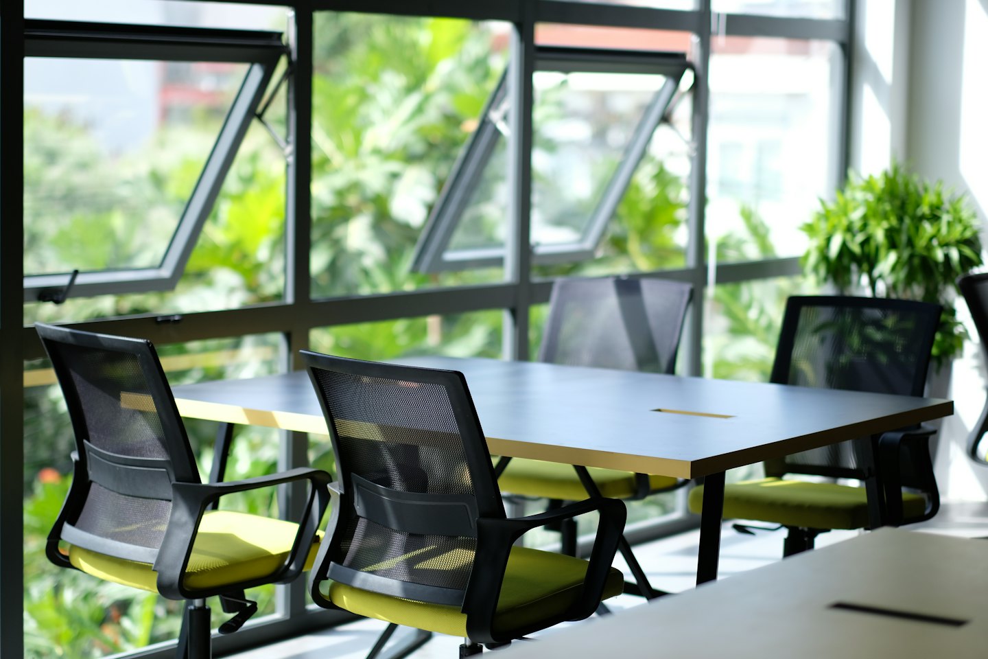 Meeting room with a long table and green chairs.